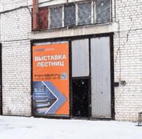Кирпичный фасад и вход в здание с вывеской «Выставка лестниц».